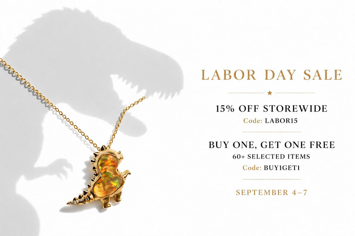 A gold necklace with a dinosaur pendant featuring an iridescent opal inlay, displayed on a clean white background with a large shadow of a T-Rex. The image includes a 'Labor Day Sale' promotional text overlay on the right side.